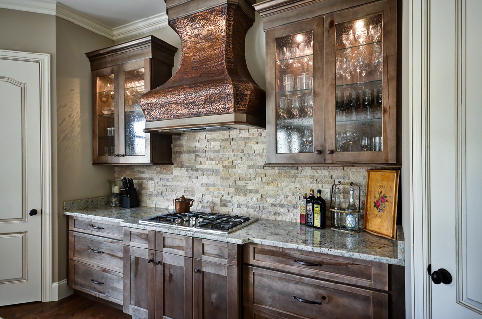 Foto på ett vintage kök, med en undermonterad diskho, luckor med glaspanel, skåp i slitet trä, granitbänkskiva, beige stänkskydd, stänkskydd i sten och rostfria vitvaror