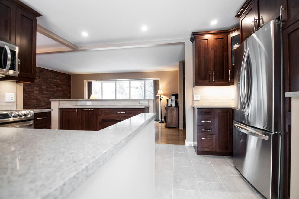Design ideas for a medium sized traditional u-shaped open plan kitchen in Ottawa with a submerged sink, shaker cabinets, engineered stone countertops, stainless steel appliances, an island, dark wood cabinets, white splashback, glass tiled splashback, ceramic flooring and beige floors.