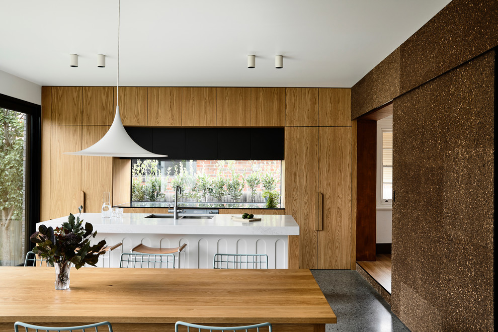 Medium sized contemporary galley kitchen/diner in Melbourne with a submerged sink, flat-panel cabinets, composite countertops, glass sheet splashback, black appliances, concrete flooring, an island, grey floors, white worktops and medium wood cabinets.