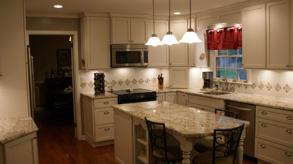 Foto di una cucina chic con lavello sottopiano, ante con riquadro incassato, ante bianche, top in granito, paraspruzzi bianco, paraspruzzi in gres porcellanato e elettrodomestici in acciaio inossidabile