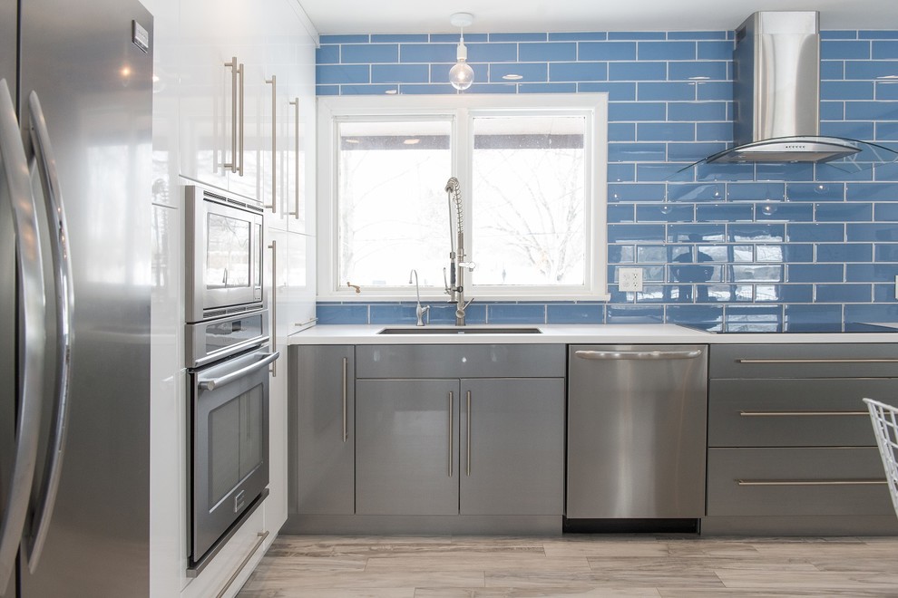 Immagine di una cucina moderna di medie dimensioni con lavello a vasca singola, paraspruzzi blu, paraspruzzi con piastrelle di vetro, elettrodomestici in acciaio inossidabile e pavimento con piastrelle in ceramica