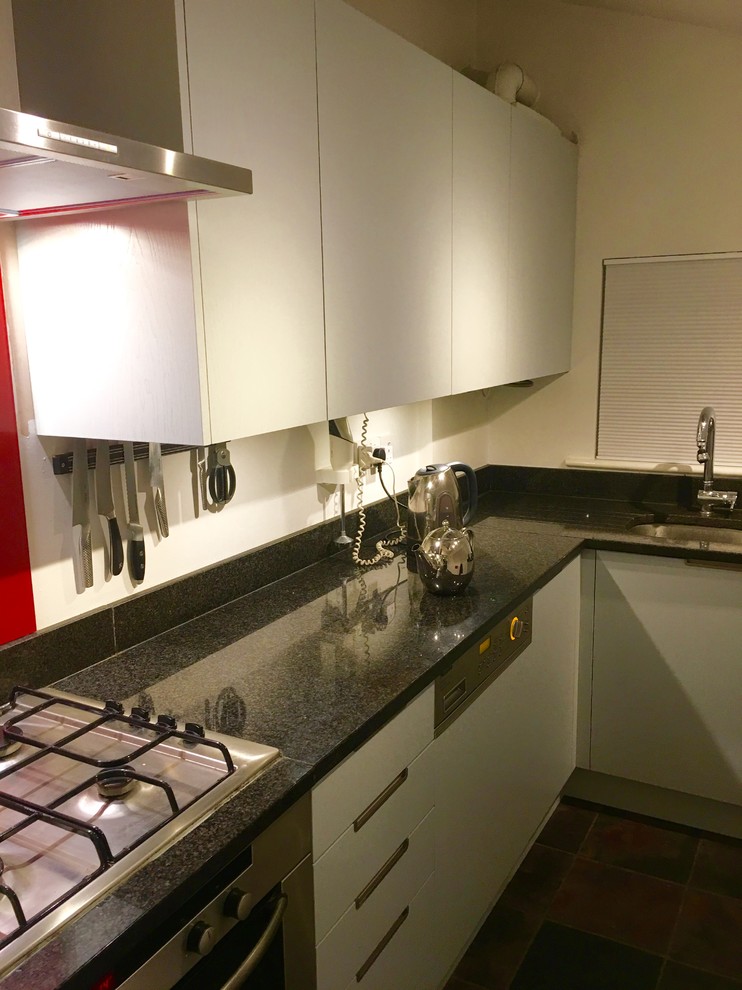 Immagine di una cucina chic con lavello sottopiano, ante lisce, top in granito, paraspruzzi rosso, paraspruzzi con lastra di vetro e pavimento in ardesia