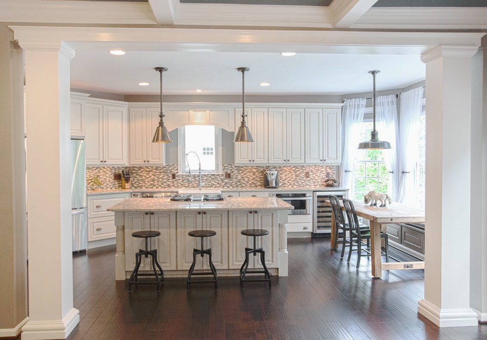 Example of a mid-sized cottage l-shaped dark wood floor eat-in kitchen design in DC Metro with a farmhouse sink, white cabinets, granite countertops, multicolored backsplash, mosaic tile backsplash, stainless steel appliances, raised-panel cabinets and an island