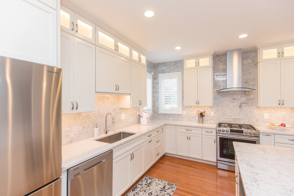 Inspiration for a mid-sized timeless l-shaped medium tone wood floor and brown floor eat-in kitchen remodel in DC Metro with an undermount sink, recessed-panel cabinets, white cabinets, marble countertops, gray backsplash, marble backsplash, stainless steel appliances and an island