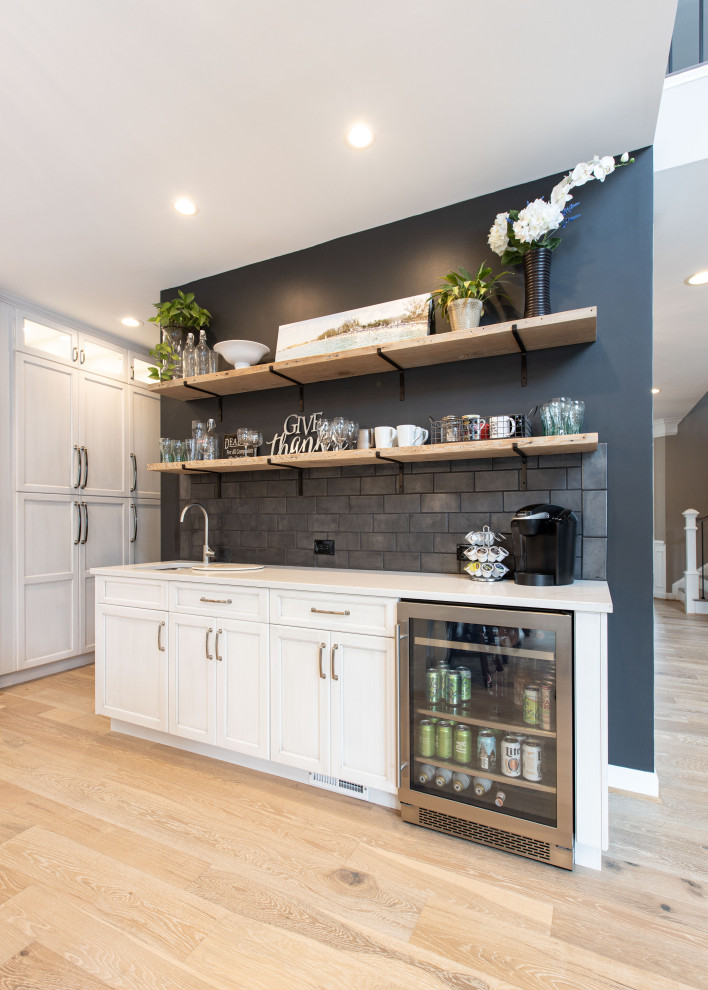 Large elegant u-shaped light wood floor and beige floor enclosed kitchen photo in DC Metro with recessed-panel cabinets, light wood cabinets, marble countertops, black backsplash, subway tile backsplash, paneled appliances, an island and white countertops