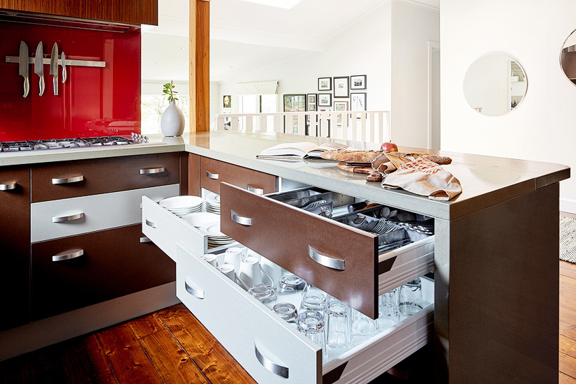 Design ideas for a medium sized eclectic u-shaped kitchen/diner in Melbourne with red splashback, glass sheet splashback, stainless steel appliances, medium hardwood flooring and an island.