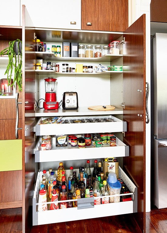 Mittelgroße Eklektische Küche in U-Form mit Küchenrückwand in Rot, Glasrückwand, Küchengeräten aus Edelstahl, braunem Holzboden, Kücheninsel und Vorratsschrank in Melbourne