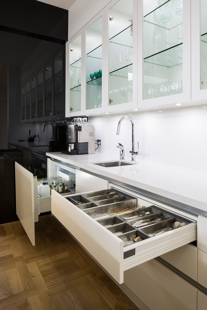 Foto på ett stort funkis kök, med en undermonterad diskho, marmorbänkskiva, vitt stänkskydd, glaspanel som stänkskydd, rostfria vitvaror, ljust trägolv och en köksö