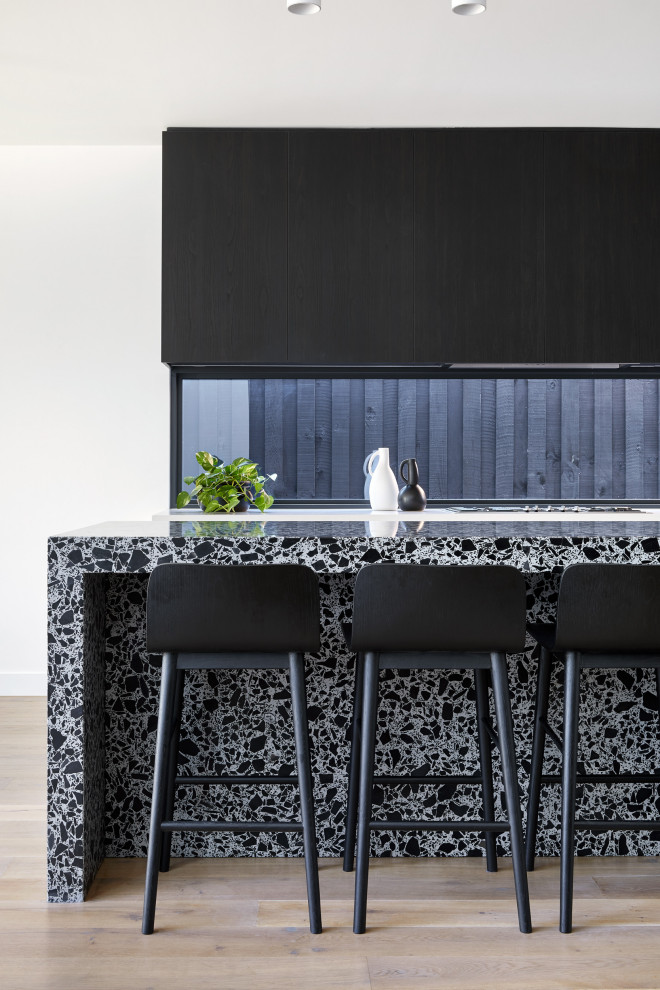 Contemporary kitchen in Melbourne with flat-panel cabinets, black cabinets, window splashback, light hardwood flooring, an island, beige floors and multicoloured worktops.
