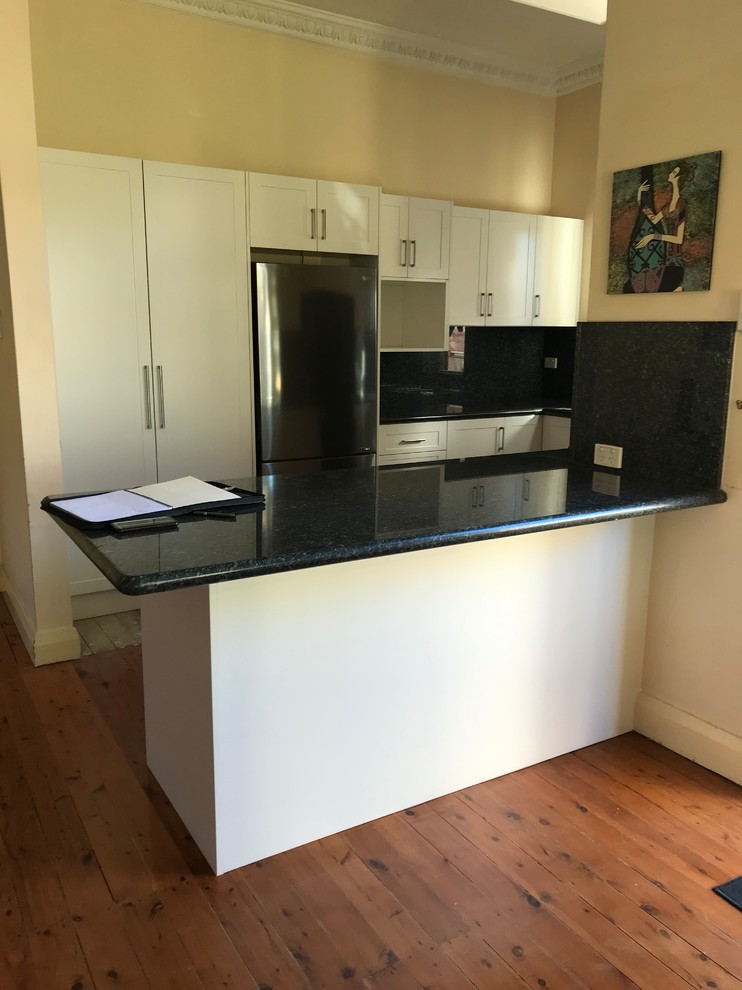 Moderne Küche in U-Form mit Vorratsschrank, Schrankfronten im Shaker-Stil, weißen Schränken, Küchenrückwand in Schwarz und schwarzer Arbeitsplatte in Sydney