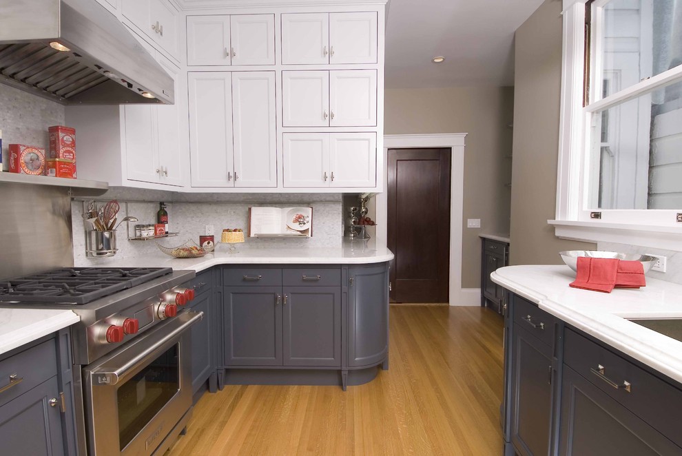 Cette photo montre une cuisine grise et blanche tendance avec un électroménager en acier inoxydable, un placard avec porte à panneau encastré et des portes de placard grises.