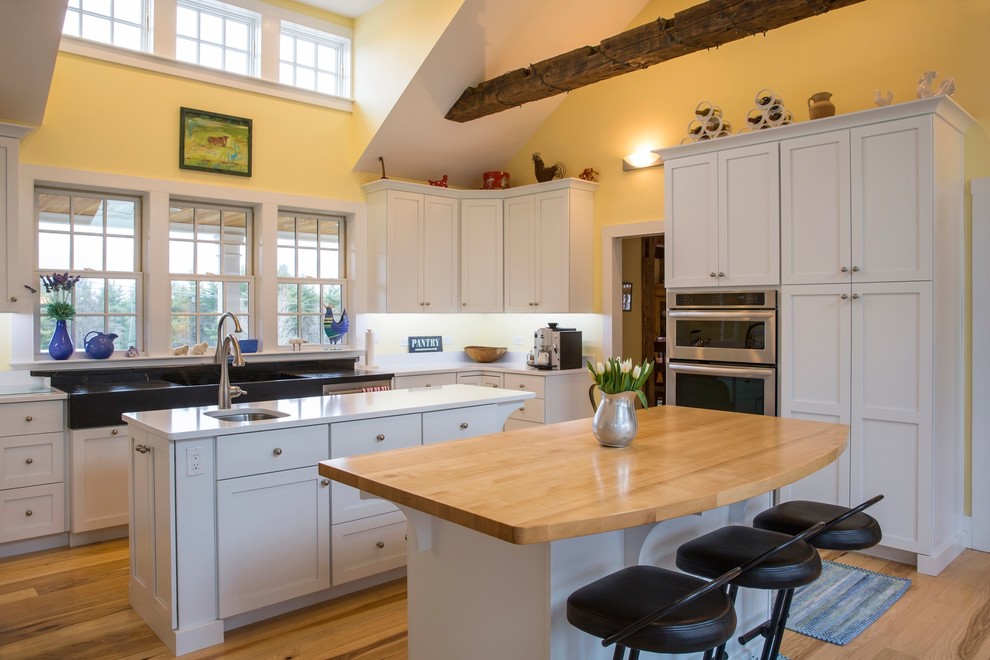 Eat-in kitchen - large country u-shaped light wood floor eat-in kitchen idea in Boston with a farmhouse sink, flat-panel cabinets, white cabinets, quartz countertops, stainless steel appliances and two islands