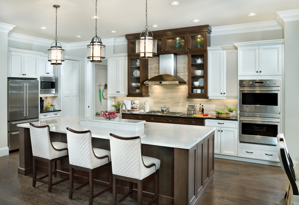 Example of a large transitional l-shaped dark wood floor open concept kitchen design in Cincinnati with an undermount sink, recessed-panel cabinets, white cabinets, quartz countertops, beige backsplash, stainless steel appliances, an island and limestone backsplash