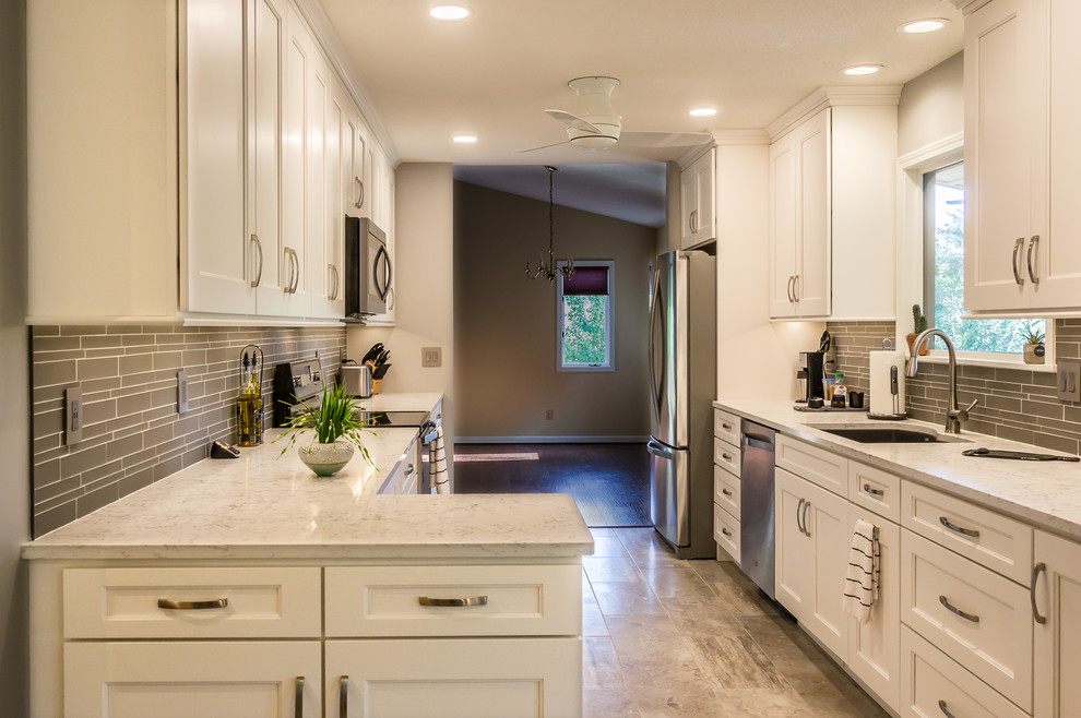 Exempel på ett mellanstort klassiskt vit vitt kök, med en dubbel diskho, skåp i shakerstil, vita skåp, granitbänkskiva, grått stänkskydd, stänkskydd i glaskakel, rostfria vitvaror, klinkergolv i keramik, en köksö och beiget golv