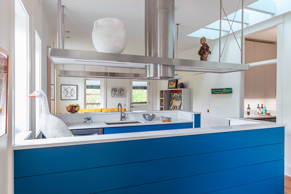 Aménagement d'une petite cuisine ouverte parallèle moderne avec un évier encastré, un placard à porte plane, des portes de placard bleues, une crédence blanche, un électroménager en acier inoxydable, un sol en bois brun, aucun îlot et un sol marron.