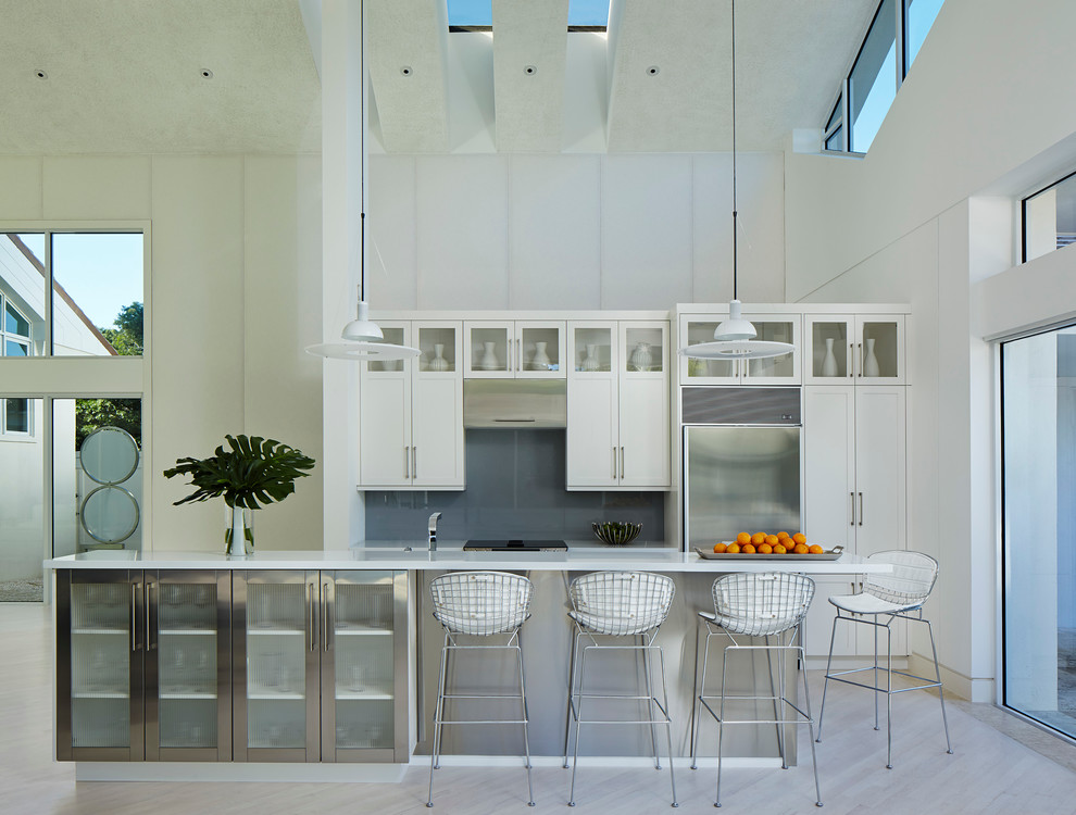 Mid-sized trendy single-wall light wood floor and beige floor open concept kitchen photo in Miami with shaker cabinets, white cabinets, gray backsplash, stainless steel appliances, an island, quartz countertops and glass sheet backsplash