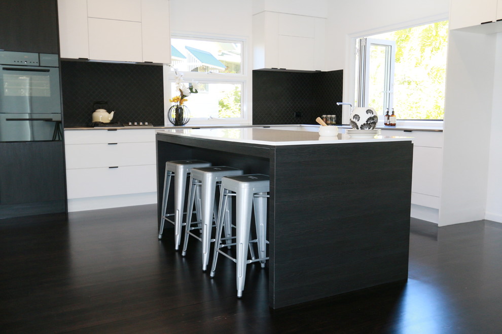 Example of a trendy dark wood floor kitchen design in Brisbane with an integrated sink, black backsplash and an island