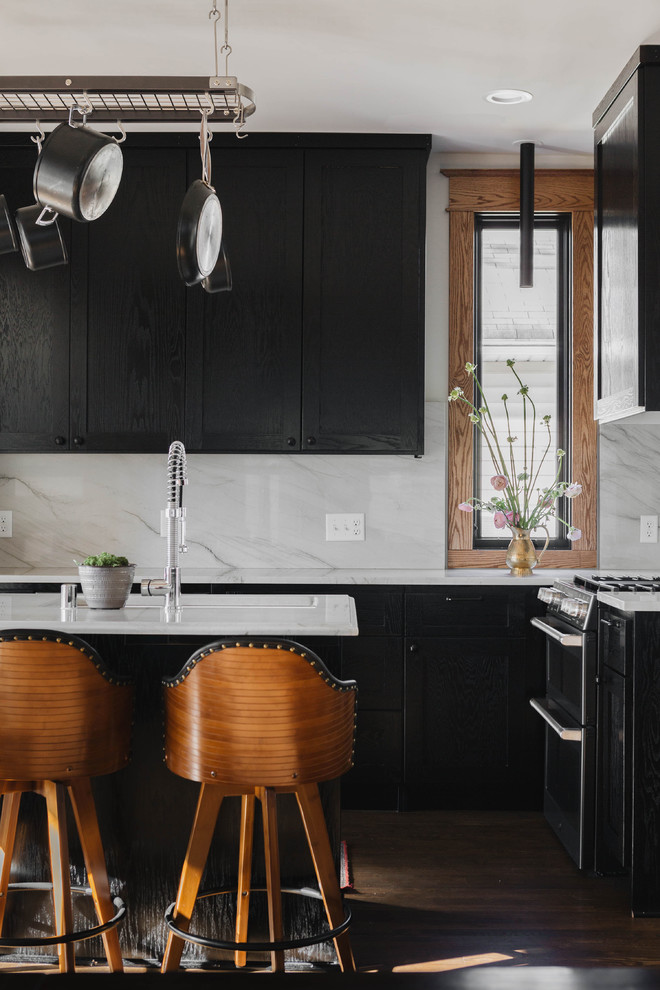 Inspiration for a transitional brown floor and dark wood floor kitchen remodel in Minneapolis with an undermount sink, black cabinets, marble countertops, white backsplash, marble backsplash, an island, white countertops, shaker cabinets and stainless steel appliances