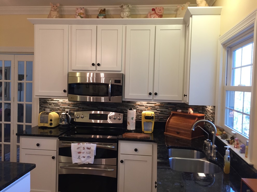 Amerikansk inredning av ett avskilt, stort u-kök, med en dubbel diskho, skåp i shakerstil, vita skåp, bänkskiva i kvarts, flerfärgad stänkskydd, stänkskydd i stickkakel, rostfria vitvaror, mellanmörkt trägolv, en köksö och brunt golv