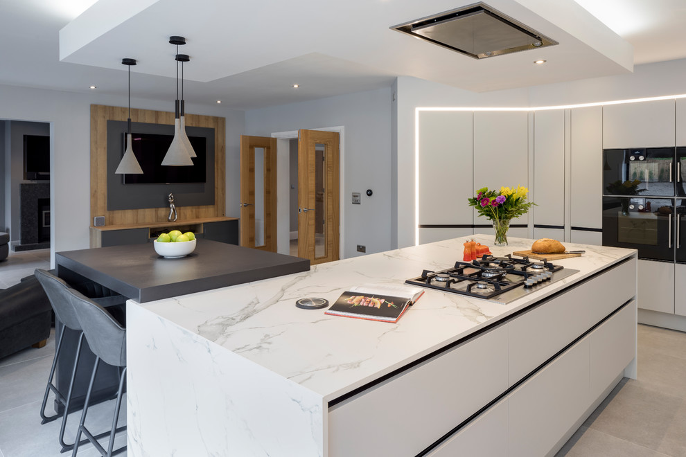 This is an example of a large contemporary open plan kitchen in West Midlands with a single-bowl sink, grey cabinets, composite countertops, white splashback, marble splashback, coloured appliances, porcelain flooring, an island and grey floors.