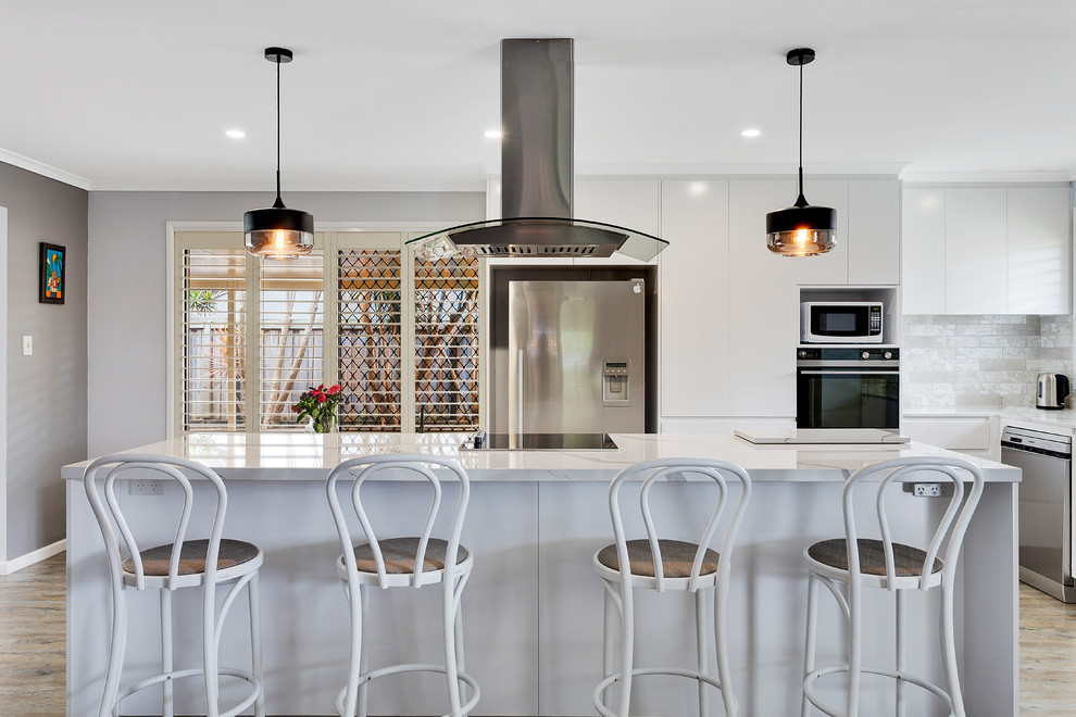 Eat-in kitchen - mid-sized transitional eat-in kitchen idea in Gold Coast - Tweed with an undermount sink, flat-panel cabinets, white cabinets, quartz countertops, gray backsplash, ceramic backsplash, stainless steel appliances, an island and white countertops