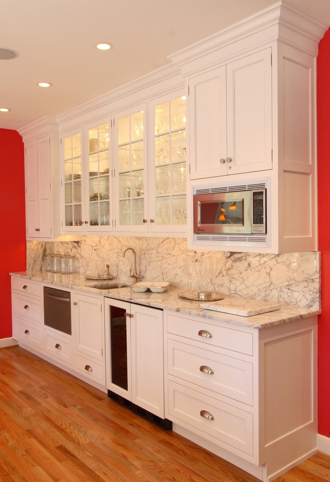 Example of a mid-sized eclectic galley medium tone wood floor kitchen pantry design in Philadelphia with an integrated sink, shaker cabinets, white cabinets, white backsplash, stone slab backsplash, stainless steel appliances and an island