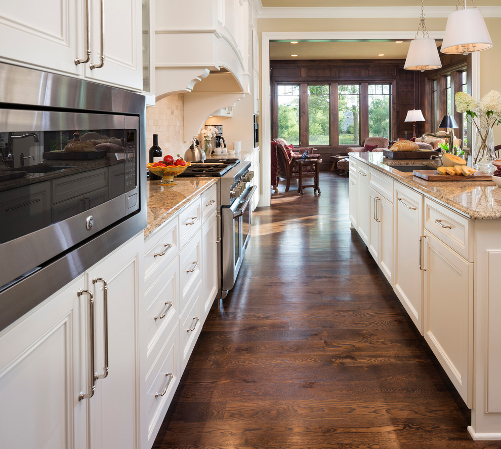 Photo of a world-inspired kitchen in Minneapolis with white cabinets, granite worktops, beige splashback, stone tiled splashback, integrated appliances and dark hardwood flooring.