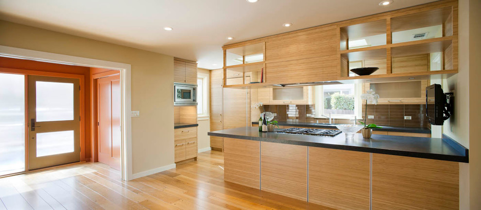 This is an example of a medium sized world-inspired galley enclosed kitchen in San Francisco with a submerged sink, flat-panel cabinets, medium wood cabinets, brown splashback, stainless steel appliances, medium hardwood flooring, engineered stone countertops and porcelain splashback.