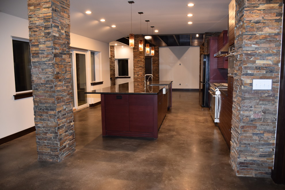 Example of a mid-sized transitional single-wall concrete floor and brown floor eat-in kitchen design in Milwaukee with a single-bowl sink, flat-panel cabinets, red cabinets, glass sheet backsplash, stainless steel appliances, an island, quartz countertops and multicolored backsplash