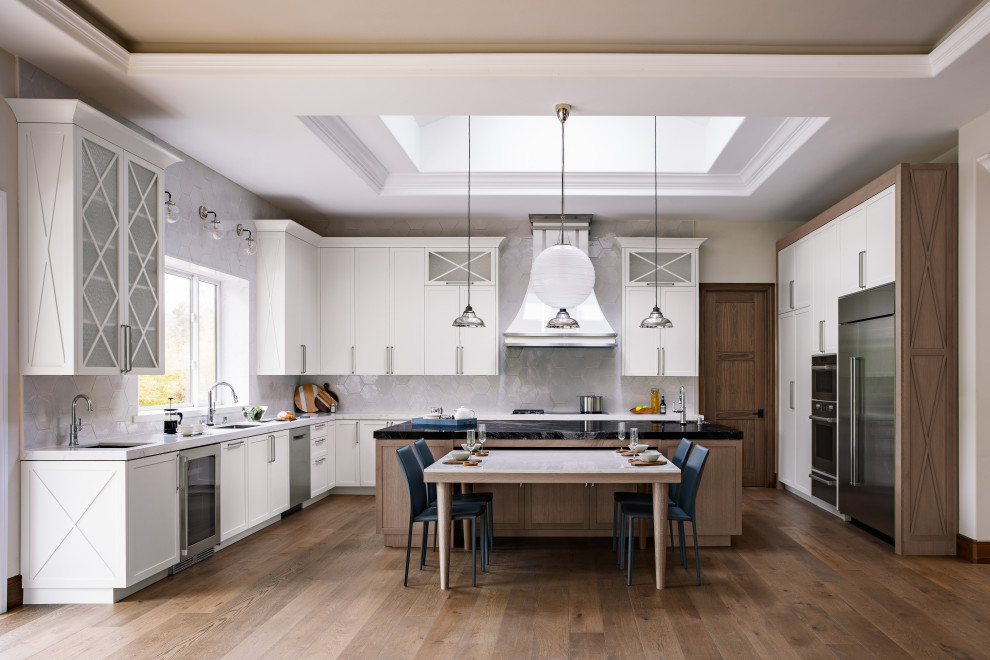 Example of a large transitional u-shaped medium tone wood floor and brown floor eat-in kitchen design in Atlanta with a drop-in sink, shaker cabinets, white cabinets, granite countertops, white backsplash, ceramic backsplash, stainless steel appliances, an island and black countertops