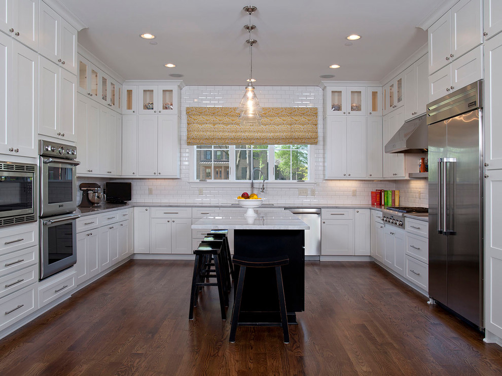 Mid-sized transitional l-shaped dark wood floor and brown floor eat-in kitchen photo in Columbus with an undermount sink, shaker cabinets, white cabinets, marble countertops, white backsplash, subway tile backsplash, stainless steel appliances and an island