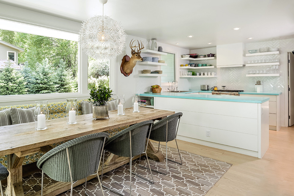Inspiration for a small eclectic u-shaped kitchen/diner in Denver with a built-in sink, flat-panel cabinets, white cabinets, laminate countertops, white splashback, metro tiled splashback, light hardwood flooring and no island.