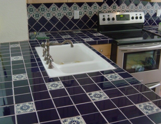 Exempel på ett mellanstort medelhavsstil kök och matrum, med en undermonterad diskho, luckor med upphöjd panel, skåp i ljust trä, kaklad bänkskiva, blått stänkskydd, stänkskydd i keramik, rostfria vitvaror och klinkergolv i terrakotta