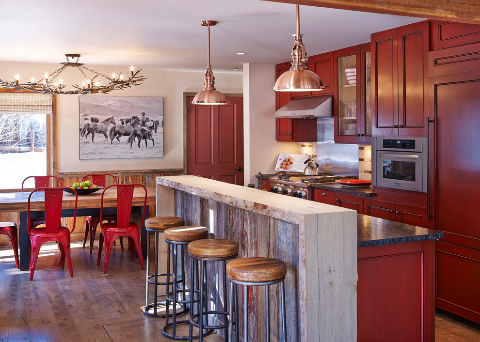 Exemple d'une cuisine américaine parallèle montagne avec des portes de placard rouges, un électroménager en acier inoxydable, îlot et un placard avec porte à panneau encastré.