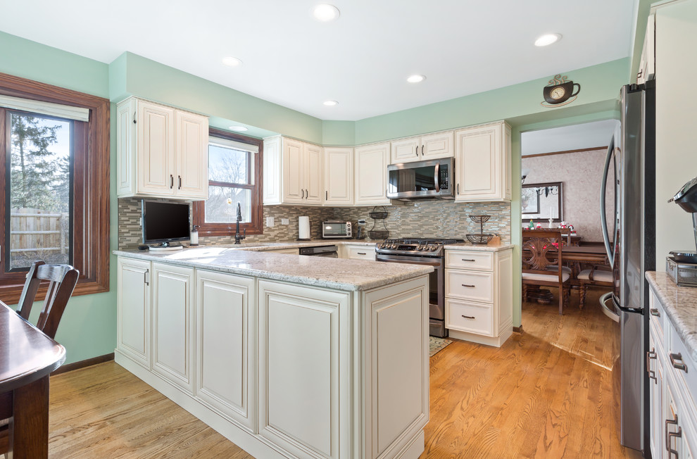 Exempel på ett stort modernt vit vitt kök, med en nedsänkt diskho, skåp i shakerstil, beige skåp, granitbänkskiva, flerfärgad stänkskydd, stänkskydd i cementkakel, rostfria vitvaror, ljust trägolv, en halv köksö och brunt golv