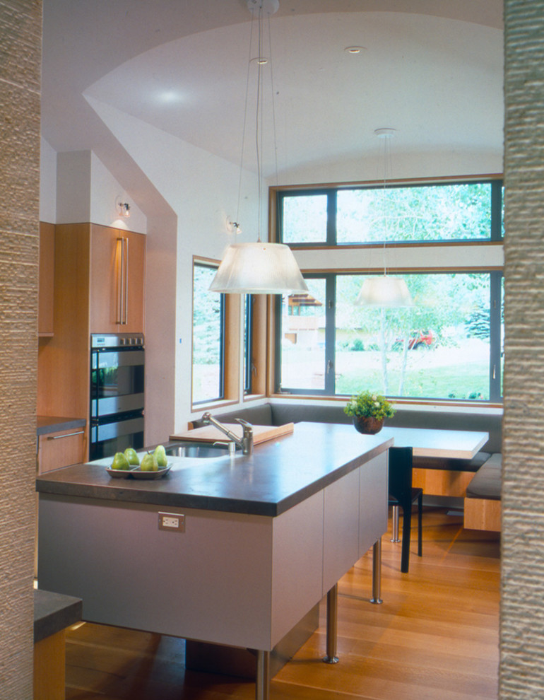 Exemple d'une grande cuisine ouverte tendance en L et bois clair avec un placard à porte plane, parquet clair et un sol marron.