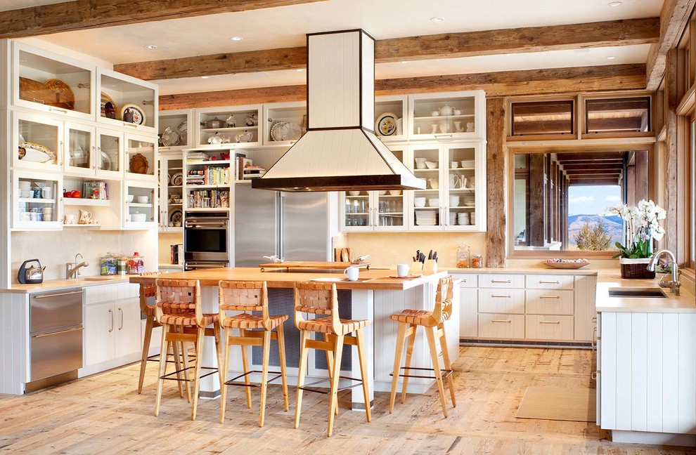 Photo of a rustic u-shaped kitchen in Denver with a submerged sink, white cabinets, stainless steel appliances, light hardwood flooring, an island and white splashback.