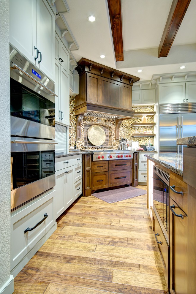 Inspiration for a large craftsman l-shaped medium tone wood floor eat-in kitchen remodel in Austin with an undermount sink, shaker cabinets, medium tone wood cabinets, granite countertops, brown backsplash, mosaic tile backsplash, stainless steel appliances and an island