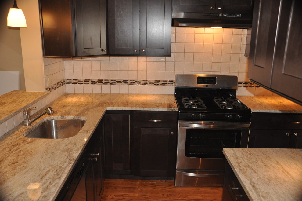Kitchen - small contemporary l-shaped medium tone wood floor kitchen idea in Philadelphia with an undermount sink, shaker cabinets, dark wood cabinets, granite countertops, white backsplash, ceramic backsplash and stainless steel appliances