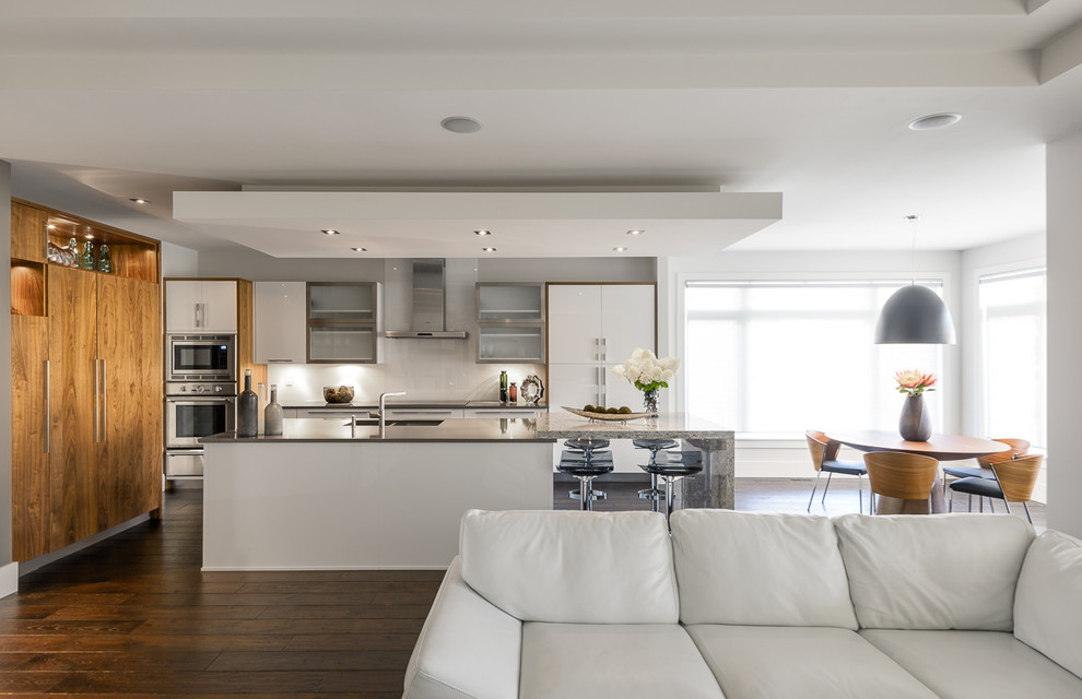 Immagine di una cucina design con ante lisce, ante bianche, paraspruzzi bianco, elettrodomestici in acciaio inossidabile e paraspruzzi con lastra di vetro