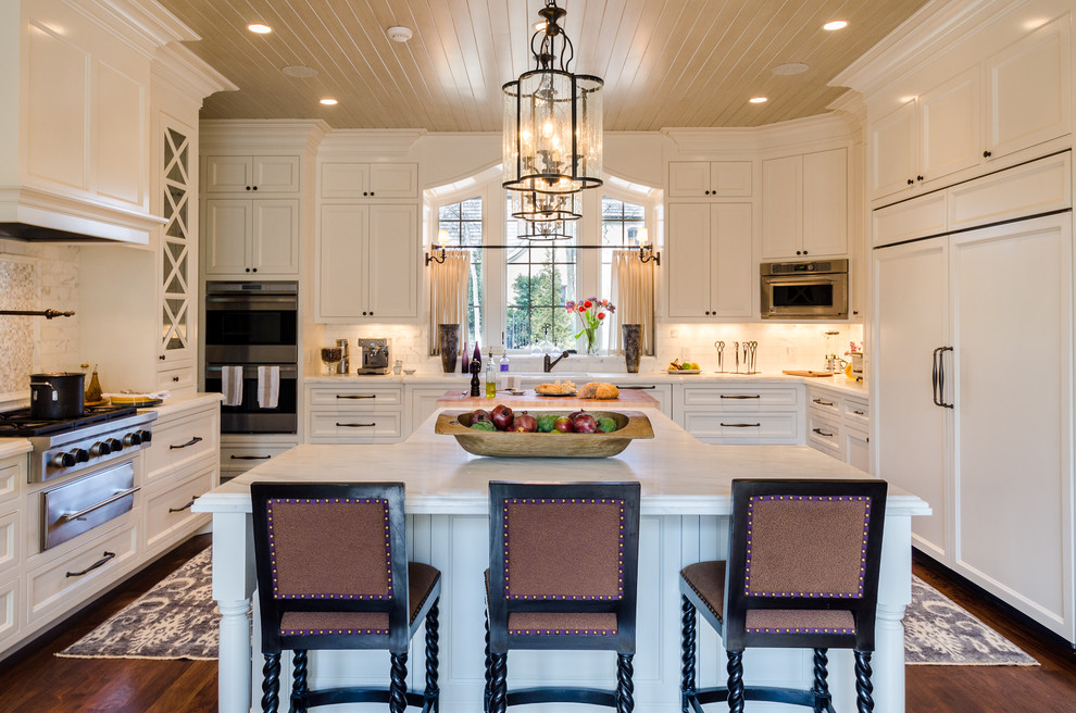 Foto på ett stort vintage kök, med luckor med infälld panel, vita skåp, marmorbänkskiva, grått stänkskydd, stänkskydd i stenkakel, rostfria vitvaror, mörkt trägolv och en köksö