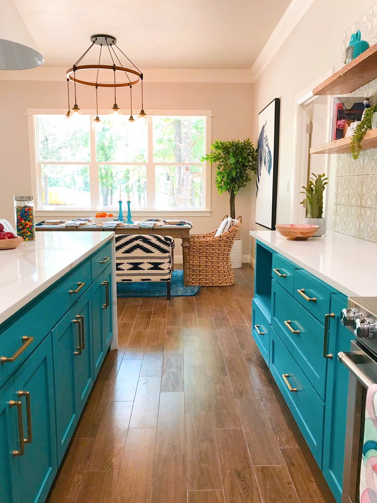 Eklektisk inredning av ett vit vitt kök, med en rustik diskho, luckor med infälld panel, blå skåp, bänkskiva i kvartsit, grått stänkskydd, stänkskydd i cementkakel, rostfria vitvaror, klinkergolv i keramik, en köksö och brunt golv