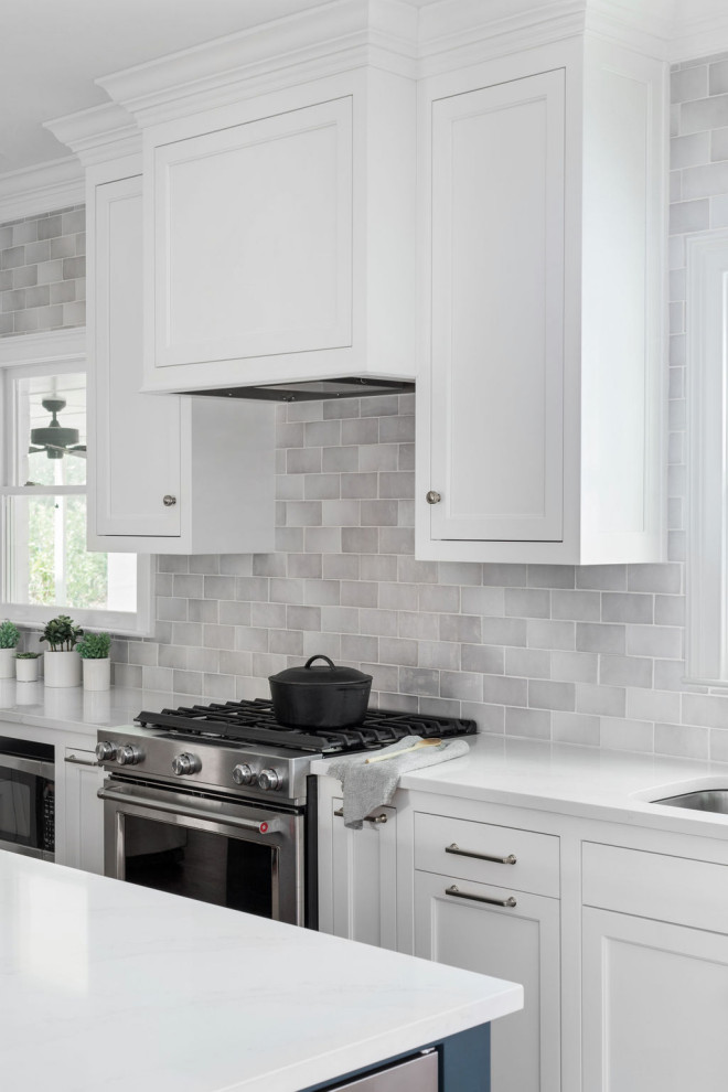 This is an example of a medium sized classic galley kitchen in Atlanta with a submerged sink, recessed-panel cabinets, white cabinets, engineered stone countertops, grey splashback, porcelain splashback, stainless steel appliances, medium hardwood flooring, an island, brown floors and white worktops.