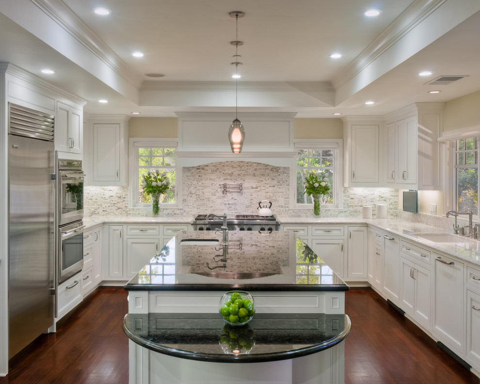 Example of a classic u-shaped dark wood floor kitchen design in San Francisco with stone tile backsplash, granite countertops, an undermount sink, recessed-panel cabinets, white cabinets, white backsplash, stainless steel appliances and an island