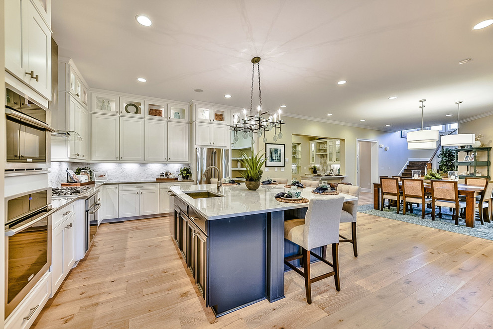 Open concept kitchen - large transitional l-shaped light wood floor open concept kitchen idea in Charlotte with an undermount sink, recessed-panel cabinets, white cabinets, quartzite countertops, multicolored backsplash, mosaic tile backsplash, stainless steel appliances and an island