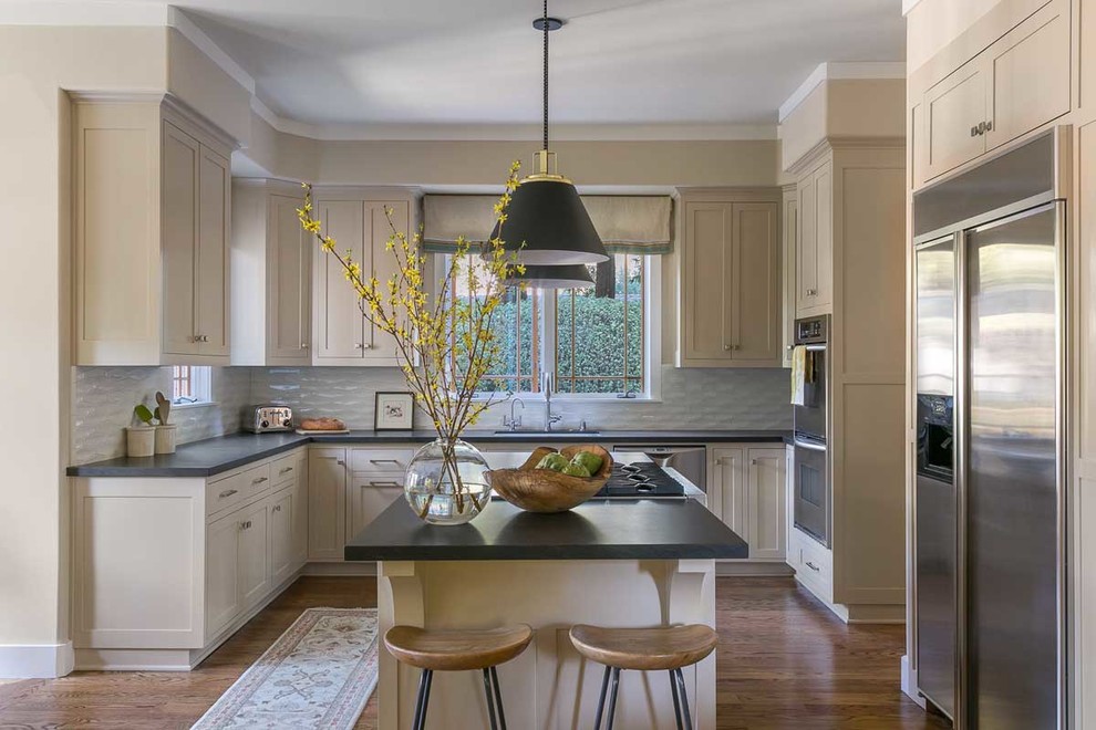Foto di una cucina classica con ante in stile shaker, ante beige, paraspruzzi bianco, elettrodomestici in acciaio inossidabile, pavimento in legno massello medio e top nero