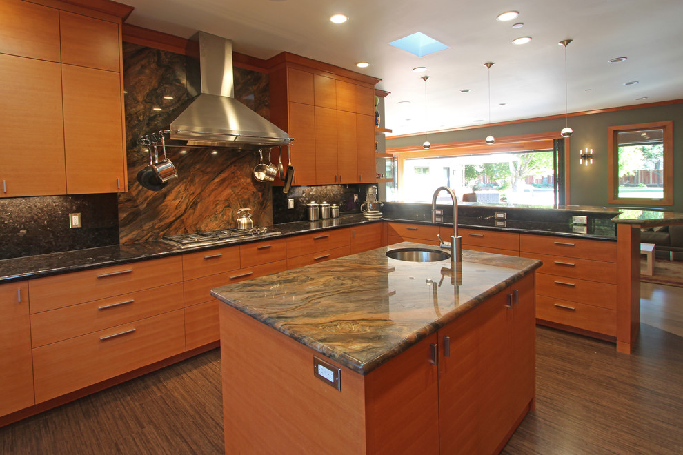 Exemple d'une cuisine ouverte tendance en bois brun avec un évier encastré, un placard à porte plane, une crédence marron et un électroménager en acier inoxydable.