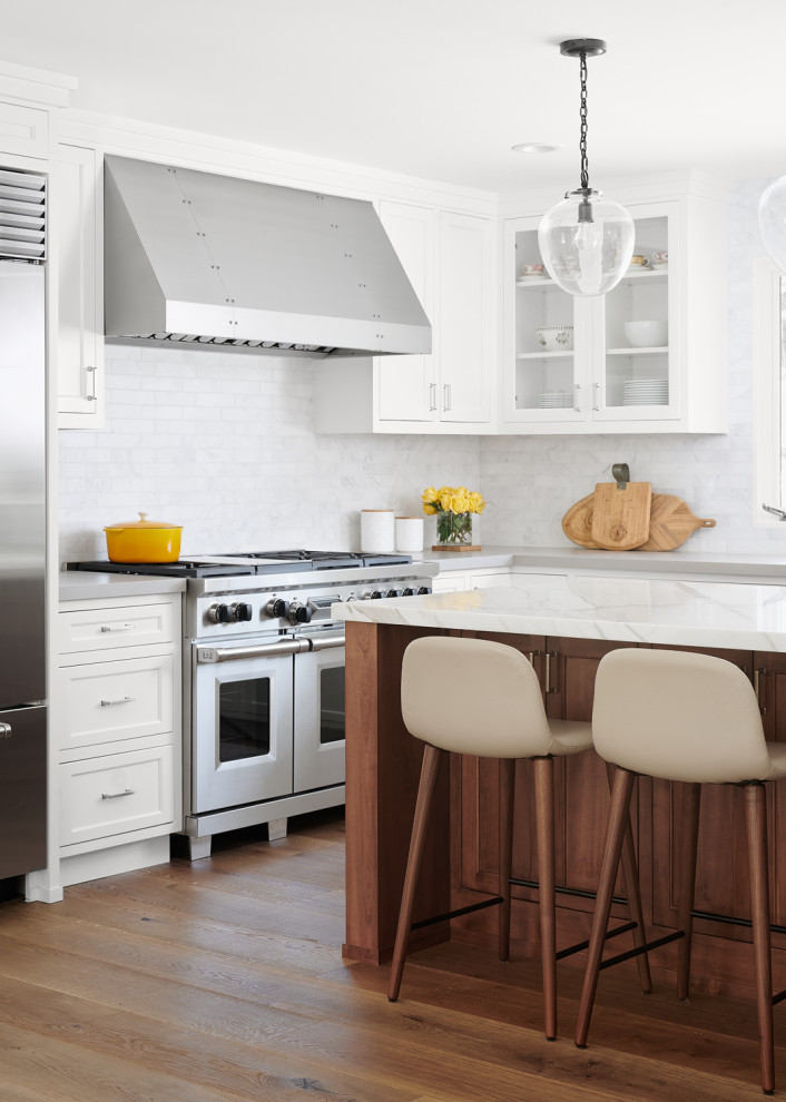 Inspiration for a transitional medium tone wood floor and brown floor kitchen remodel in San Francisco with shaker cabinets, white cabinets, white backsplash, stainless steel appliances, an island and white countertops