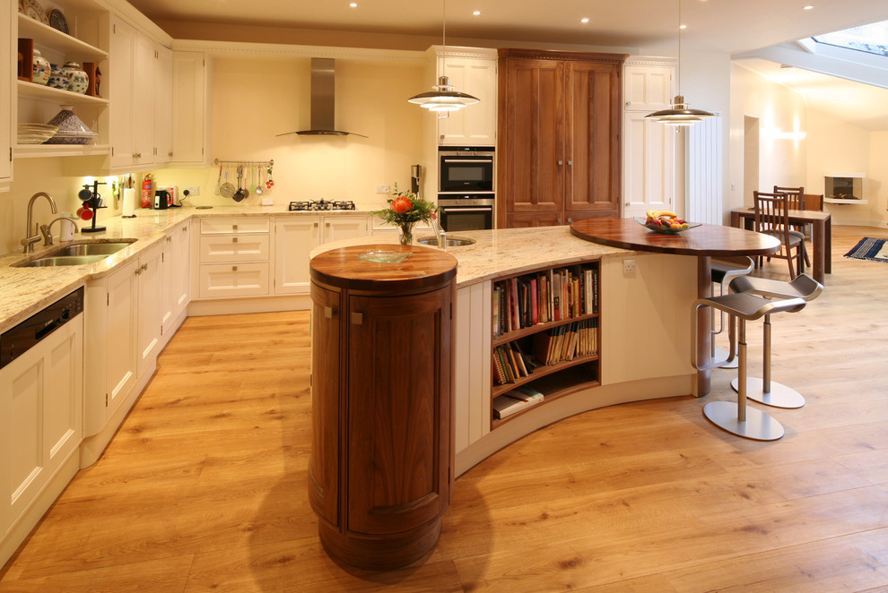 Inspiration for a large classic l-shaped kitchen/diner in Edinburgh with a double-bowl sink, raised-panel cabinets, white cabinets, granite worktops, stainless steel appliances, light hardwood flooring, an island and beige splashback.
