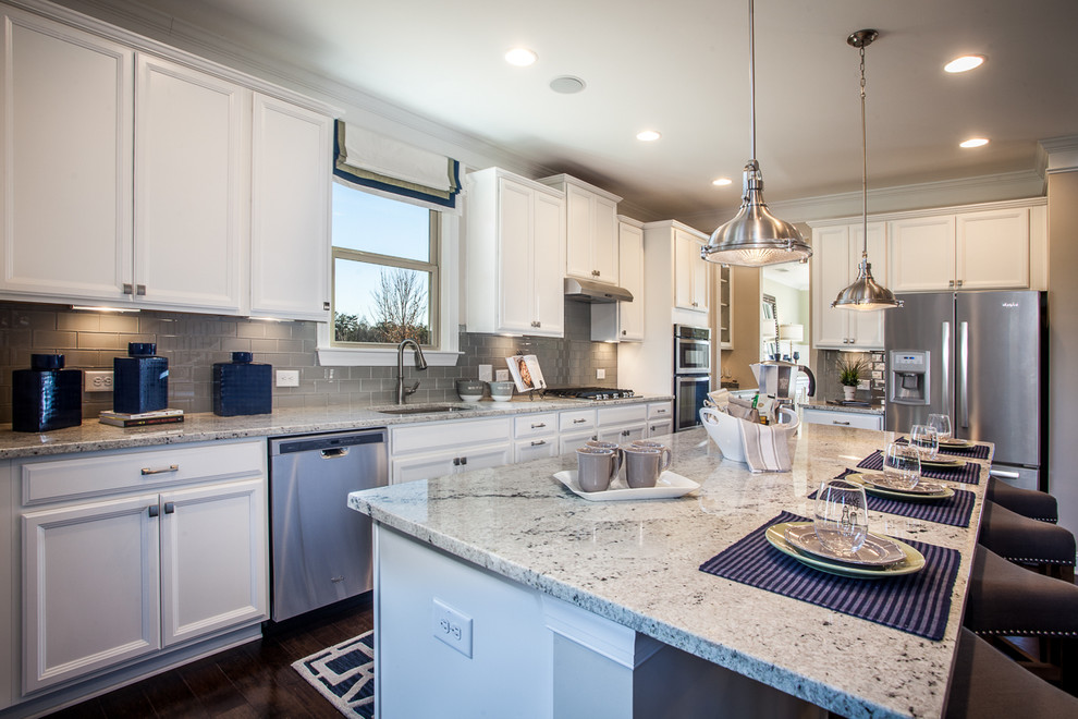 Klassische Küche in U-Form mit weißen Schränken, Küchenrückwand in Grau, Rückwand aus Metrofliesen, Küchengeräten aus Edelstahl, dunklem Holzboden und Kücheninsel in Atlanta